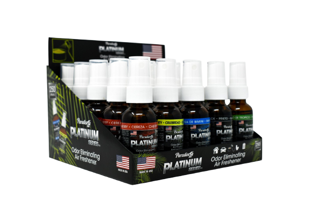 This is a display containing multiple bottles of "Paradise Platinum Series" odour eliminating air fresheners. Each bottle has a specific scent, some of which are visible like "Cherry" and "Black". The display packaging emphasises that these are made in the USA and are designed to eliminate odours.